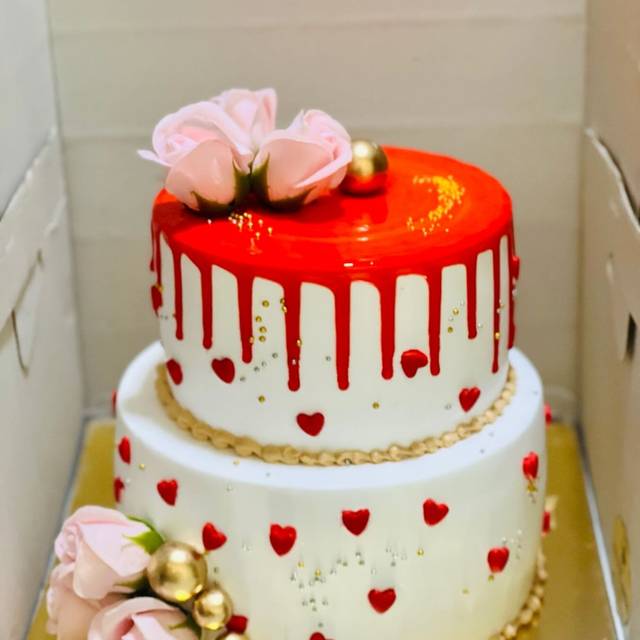 Two-tier red drip anniversary cake with roses
